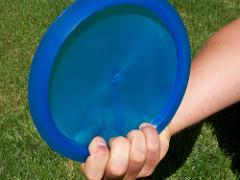 A power grip on a blue disc, all four fingers tucked tightly under the rim.