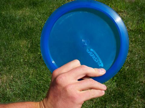 A two-finger power grip on a blue disc, two fingers tucked under the rim.