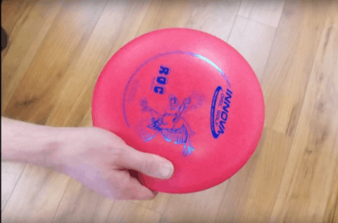 A fan grip on a pink disc, the fingers spread wide across the underside.