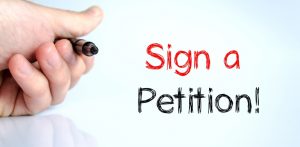 A hand holding a pen beside the handwritten words Sign a Petition.