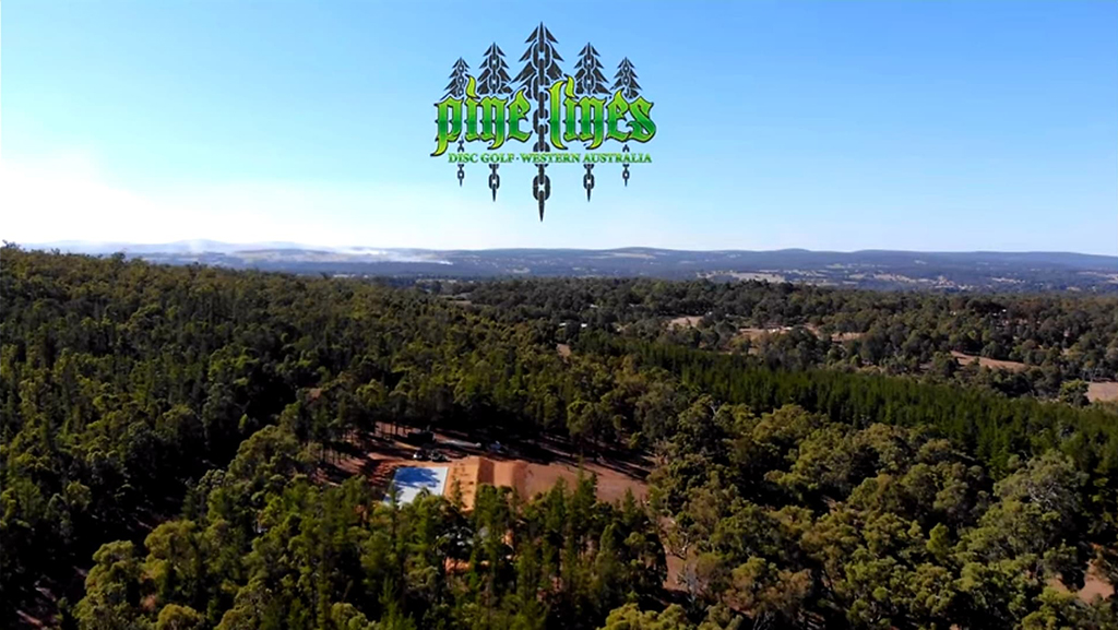 Aerial view over forested hills at Pine Lines, with the Pine Lines logo across the sky.