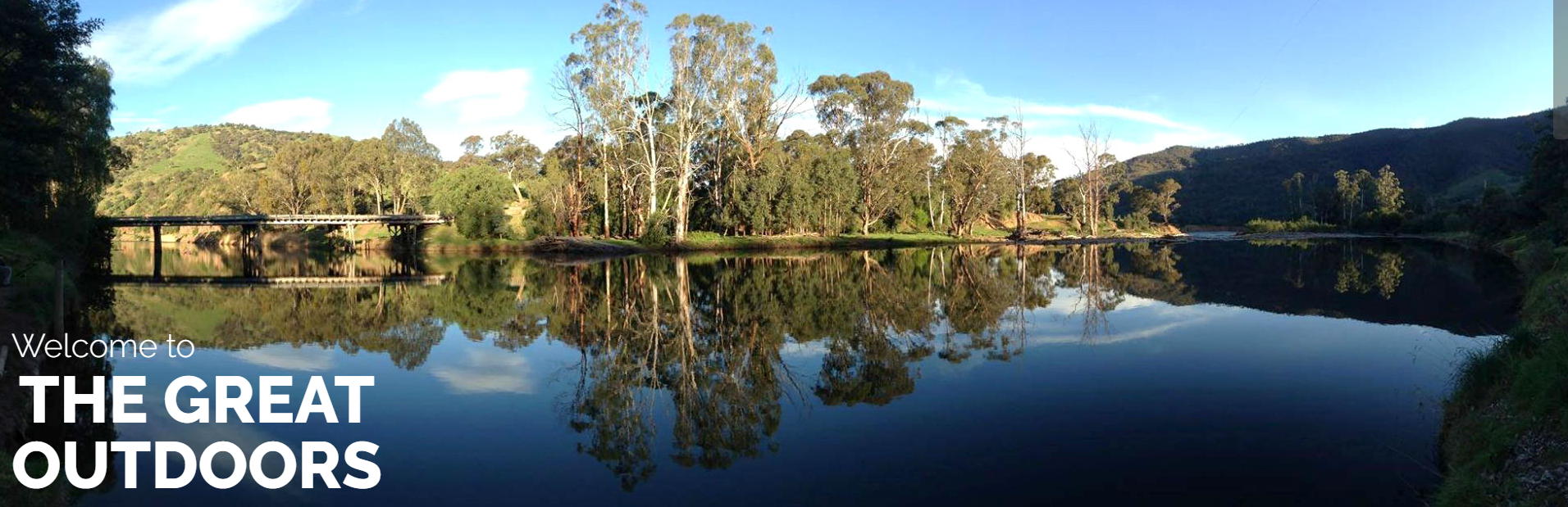 A panoramic view of a still lake fringed with trees, captioned Welcome to the Great Outdoors.