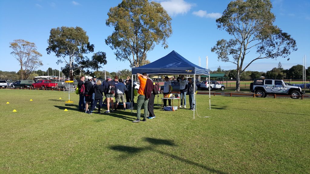 A marquee and a group of people on a green oval at a come-and-try day.
