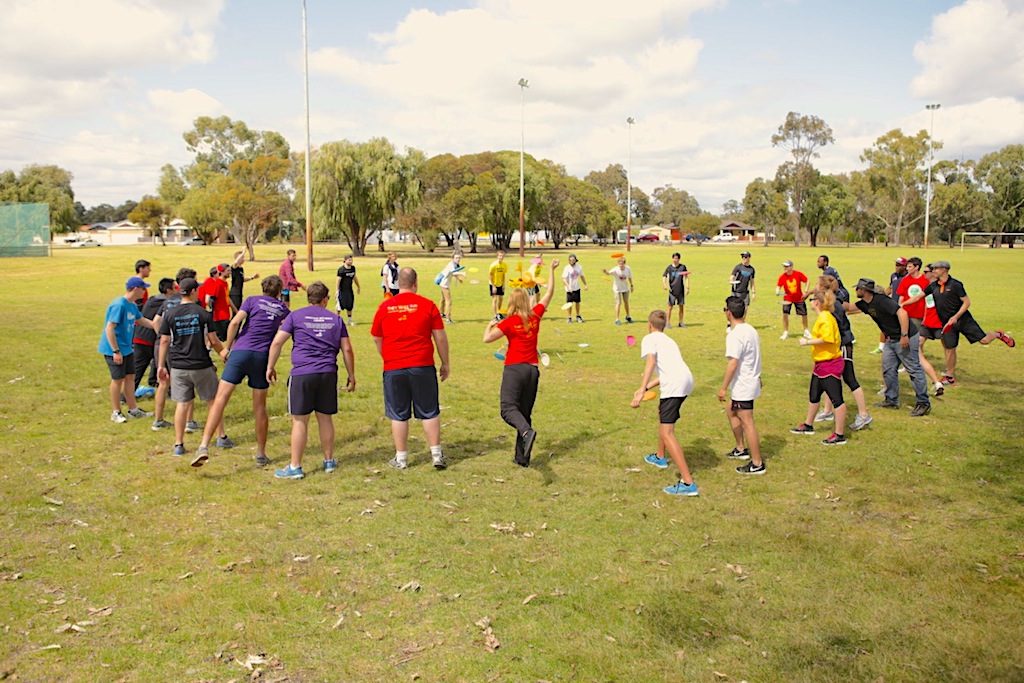 A large group of players standing in a circle on an oval for a players meeting before a round.