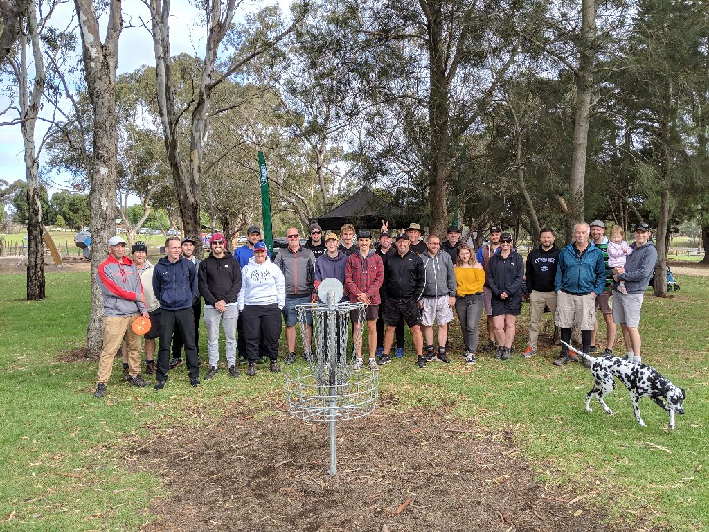 A club group posing together around a basket after a league round, a dalmatian sitting with them.