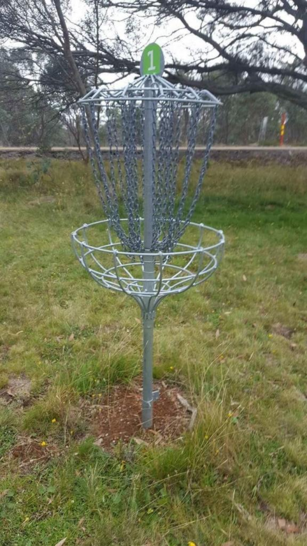A disc golf basket standing on a grassy alpine slope.