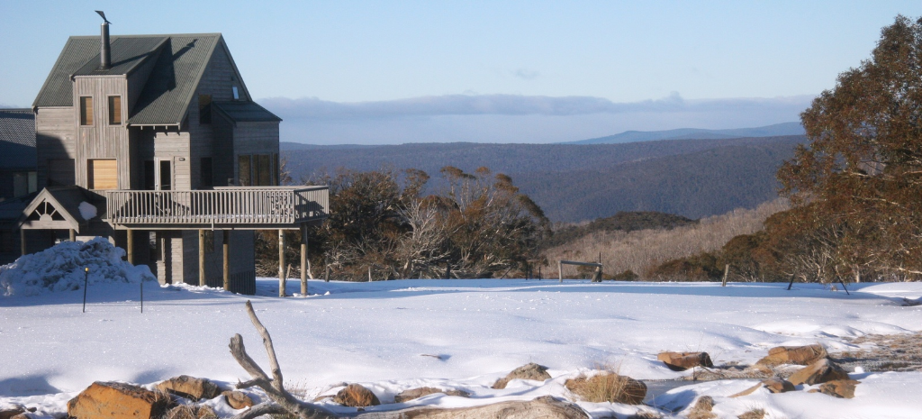 An alpine village lodge in snow, with mountain ranges stretching to the horizon.