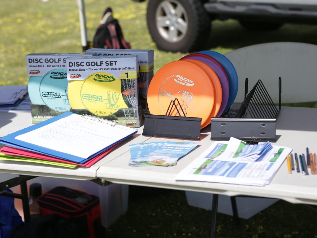 An information table laid out with boxed disc golf sets, folders and flyers.