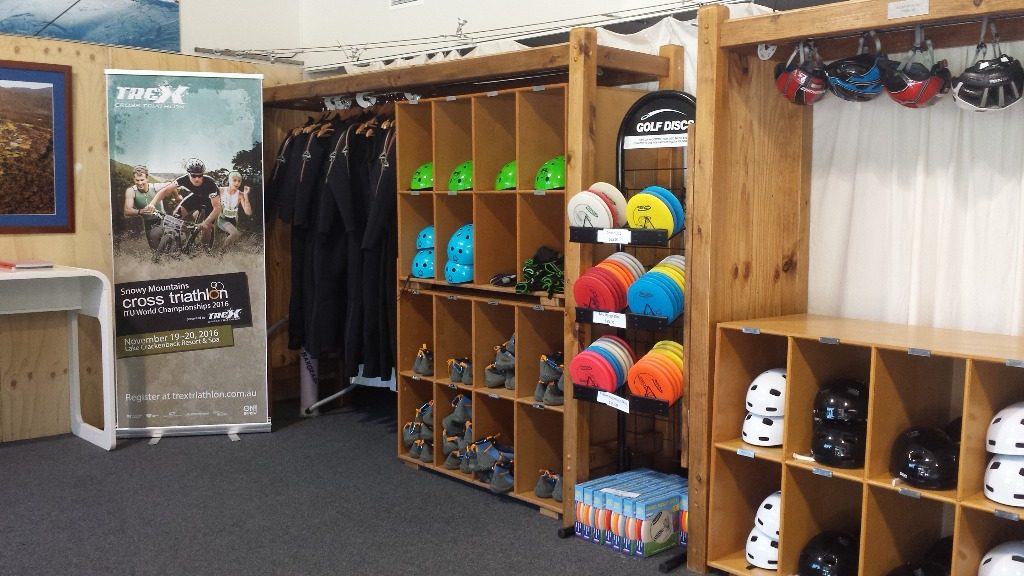 The interior of an outdoor sports shop, with discs, helmets and clothing on timber shelving.