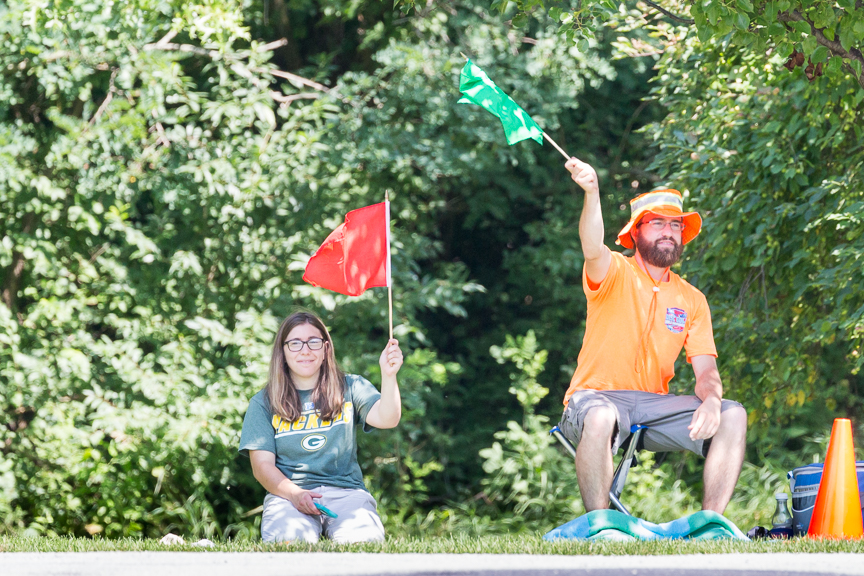 Two event volunteers in high-visibility shirts holding marshal flags.