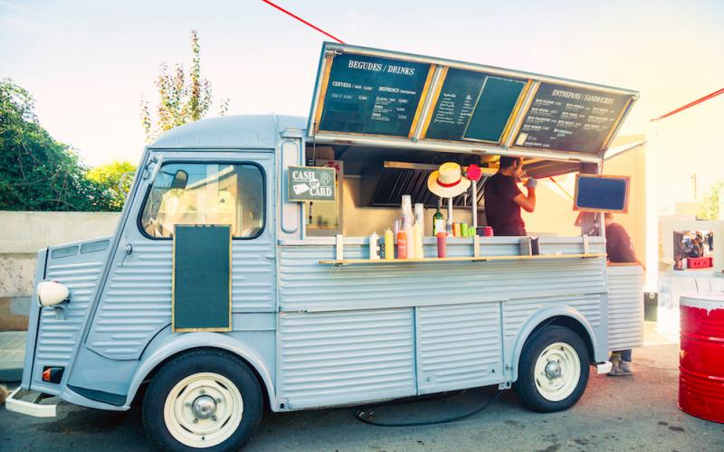 A vintage blue food van with its serving hatch open and menu boards above.