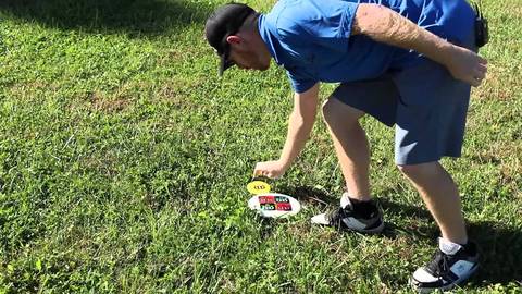 A player bending to pick up a disc from the grass.