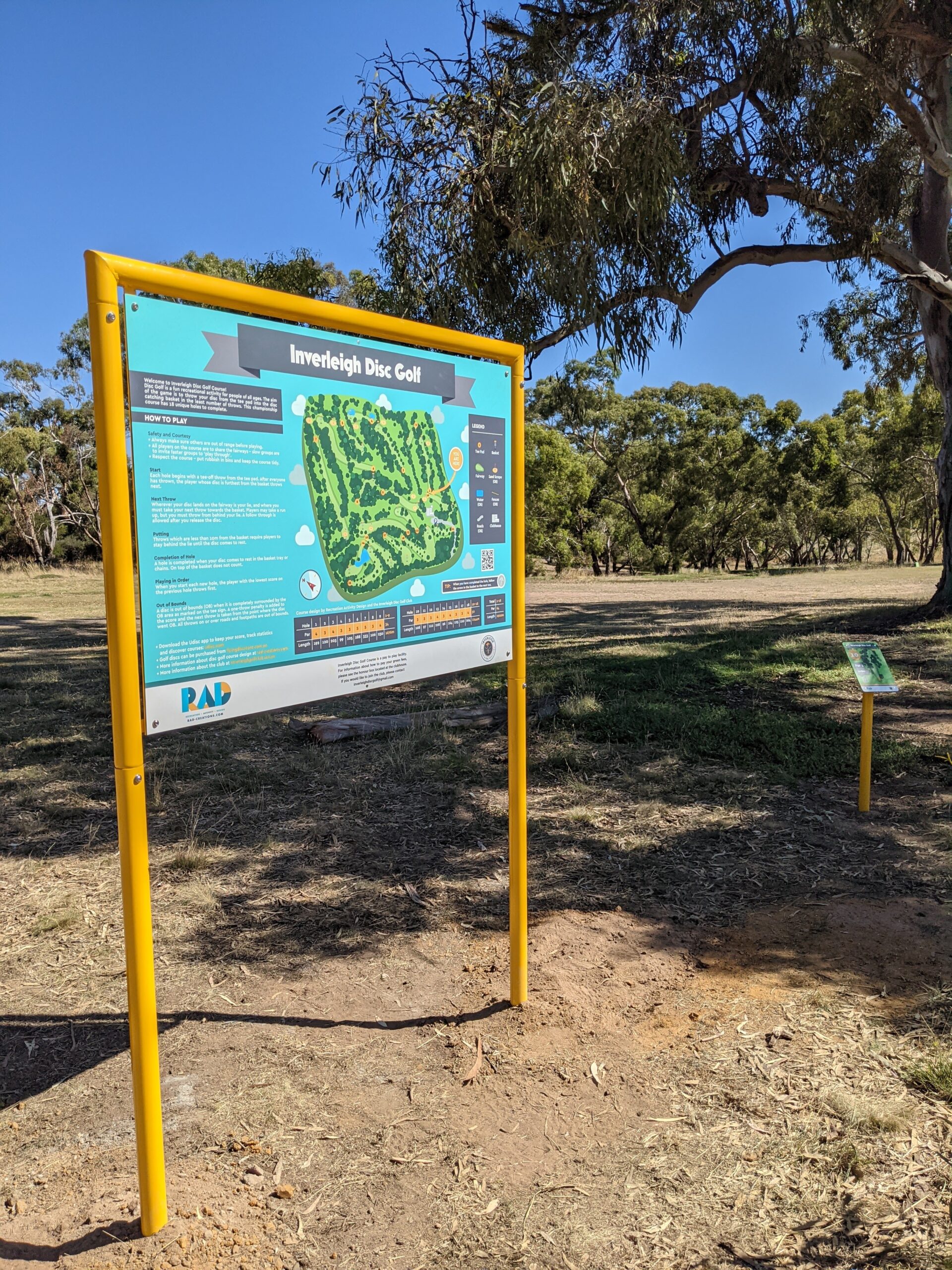 The Inverleigh Disc Golf information board mounted on yellow posts beside the course.