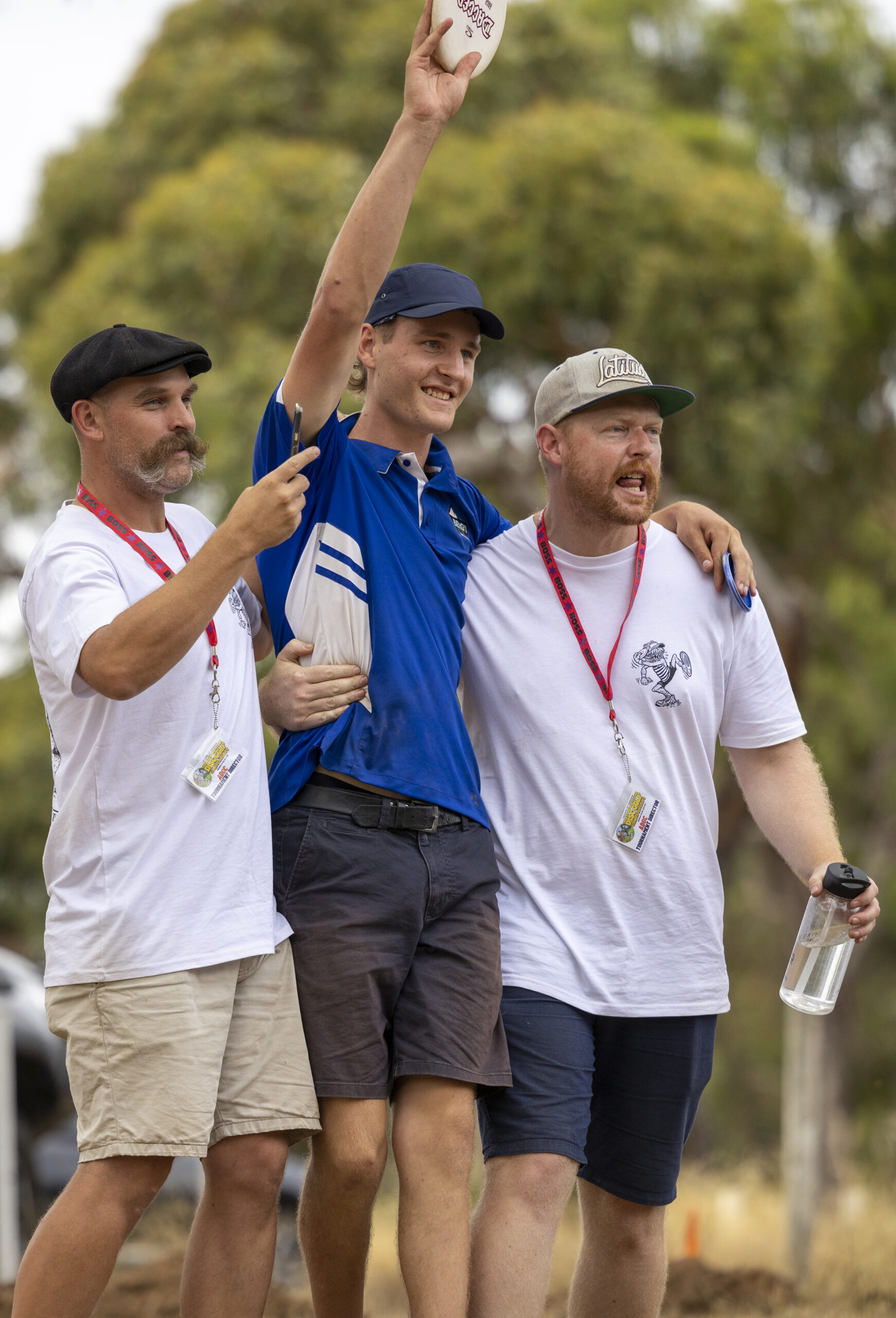 Three players celebrating together, one holding a disc above his head.
