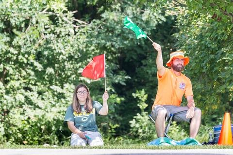 Two event volunteers holding red and green marshal flags at the edge of a fairway.