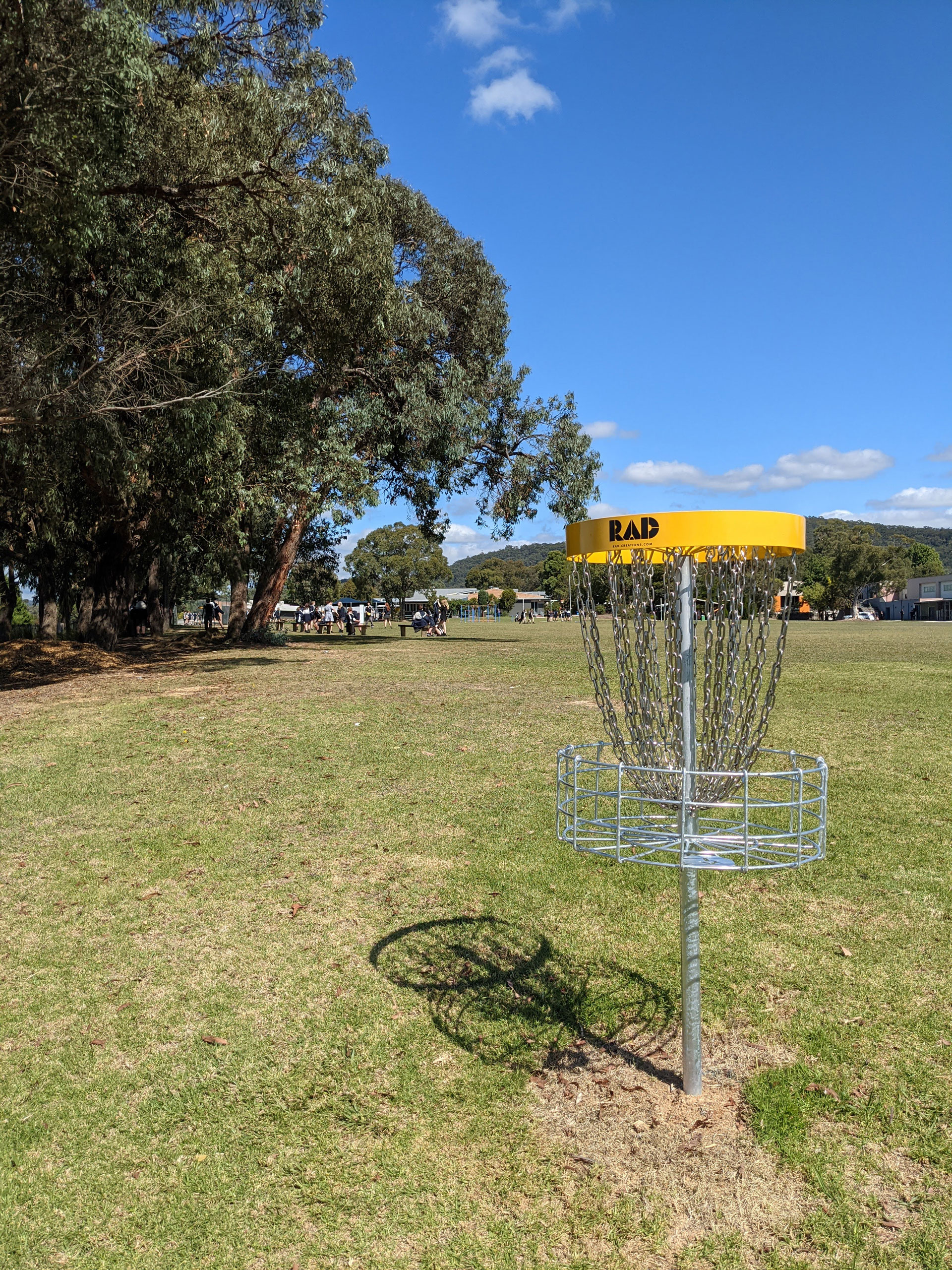 A yellow-topped RAD basket on a school field with wooded hills in the distance.