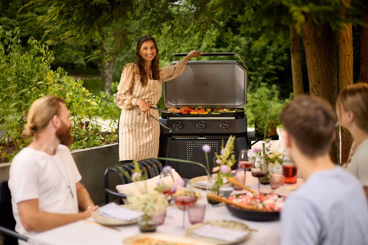 A woman standing in front of an outdoor grill.