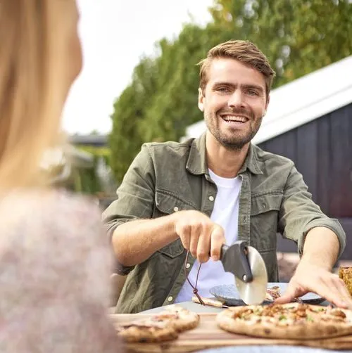 A man and woman sitting at a table eating pizza.