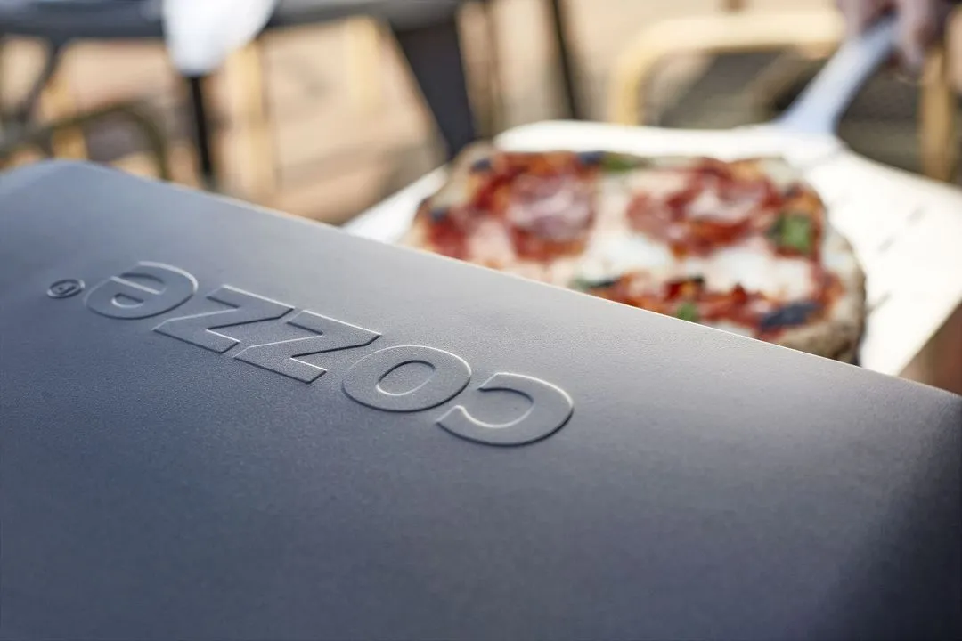 A close up of a pizza coming out of a pizza oven