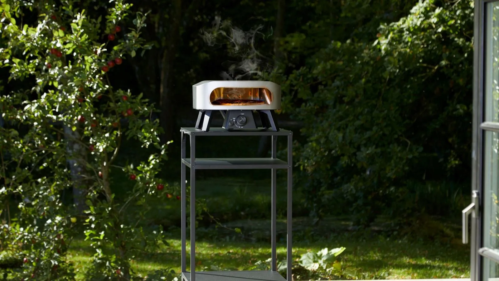 A steel pizze oven sitting on top of a metal stand.