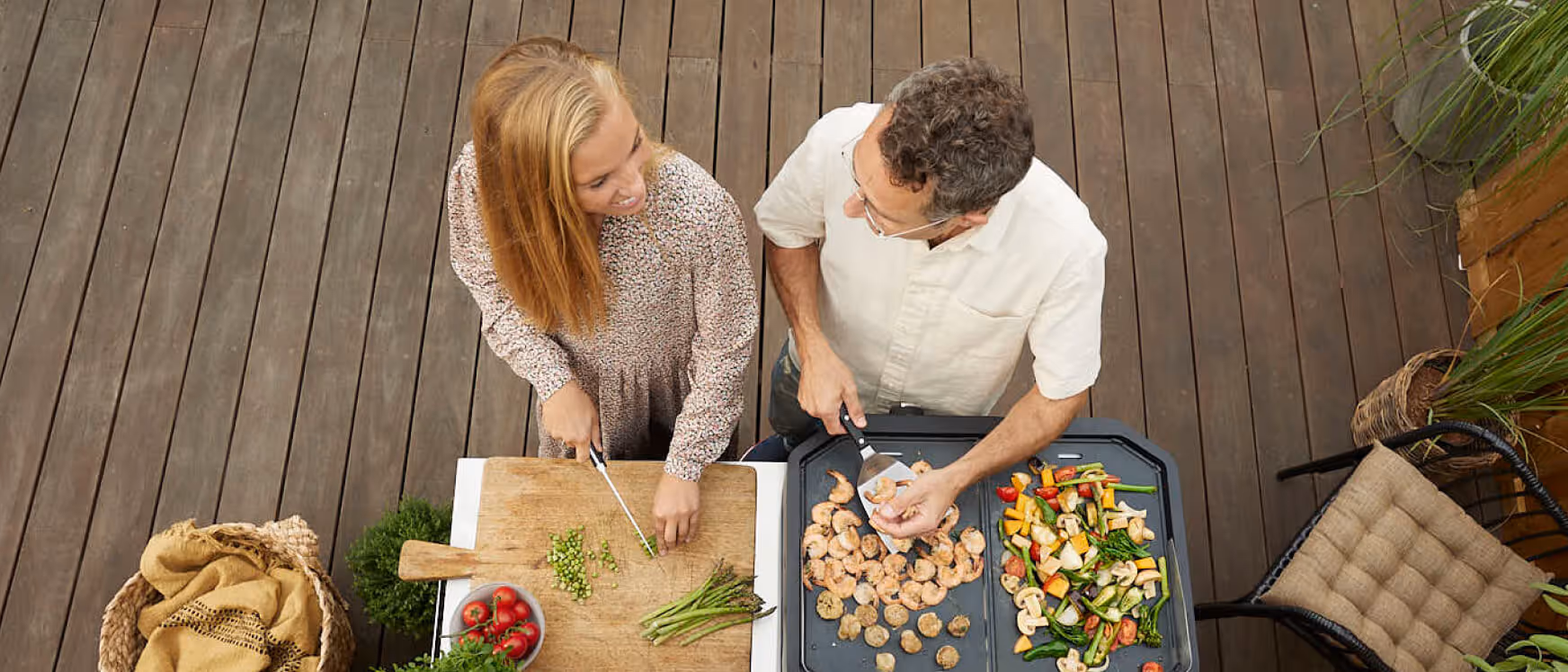 A man and a woman preparing food on a grill.