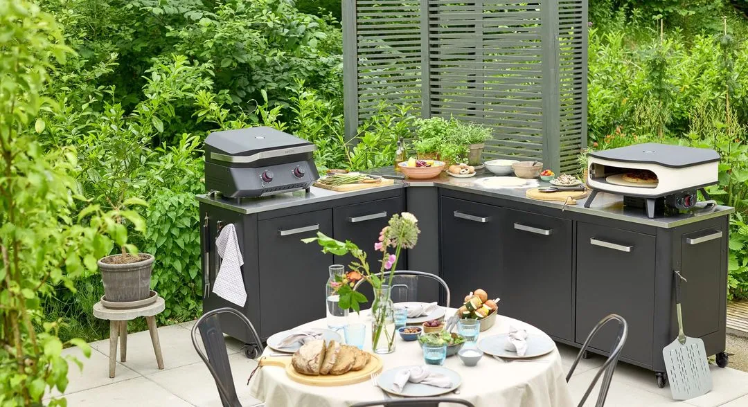 A table with a grill on top of it in the middle of a garden.