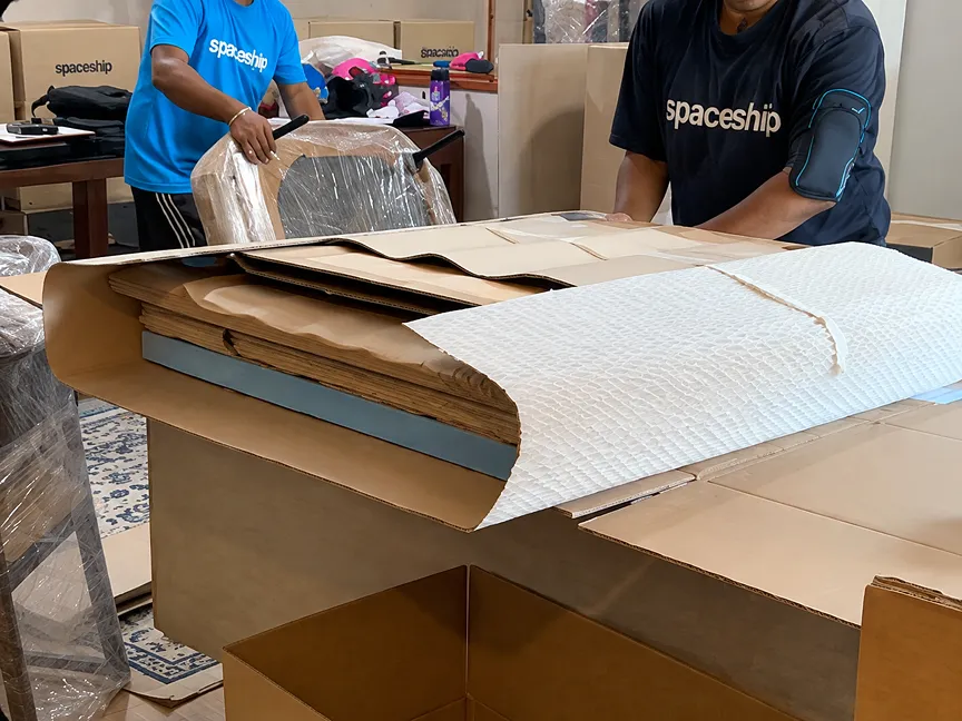 Spaceship movers preparing corrugated board protection for furniture before storage