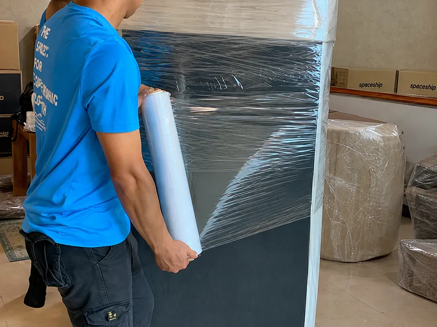 Spaceship mover wrapping furniture with stretch film to protect items during storage transport