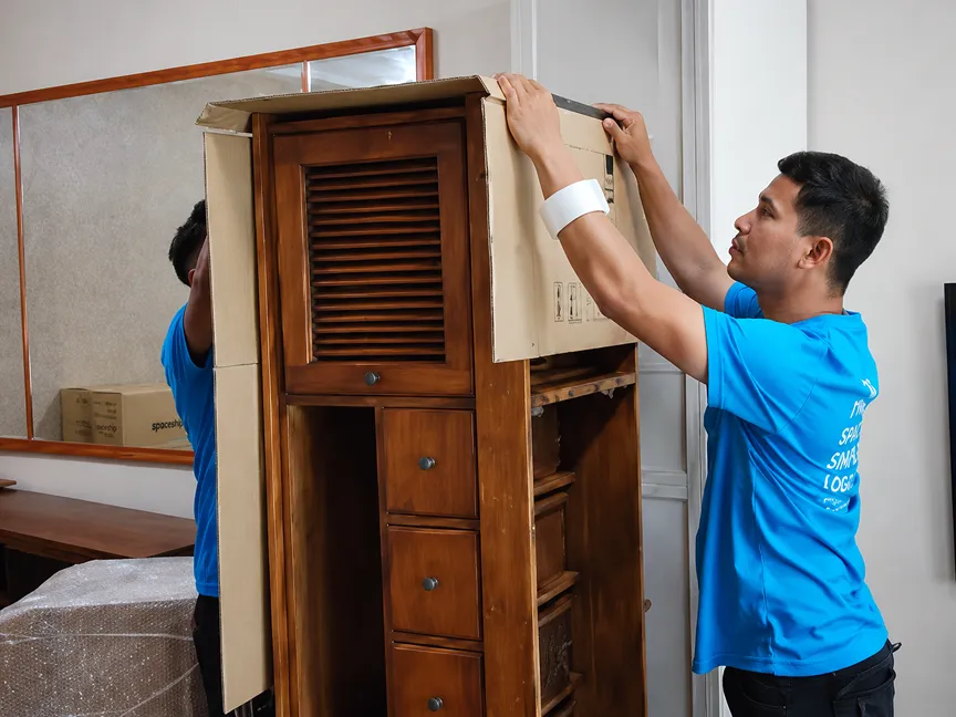 Spaceship movers adding cardboard protection to furniture before moving into storage