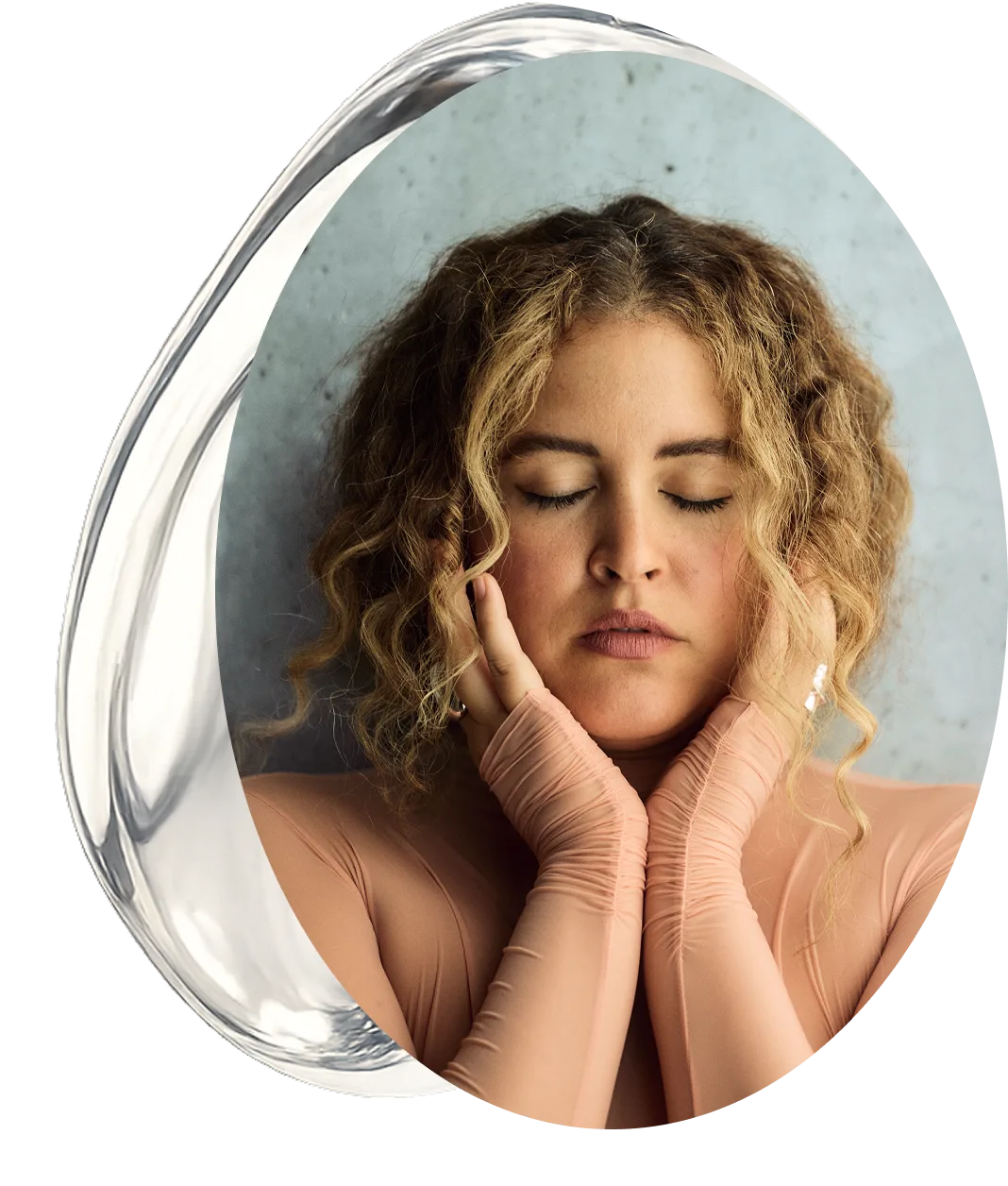 Susana with curly hair and closed eyes, wearing a beige outfit and matching gloves, posing peacefully inside an abstract glass frame