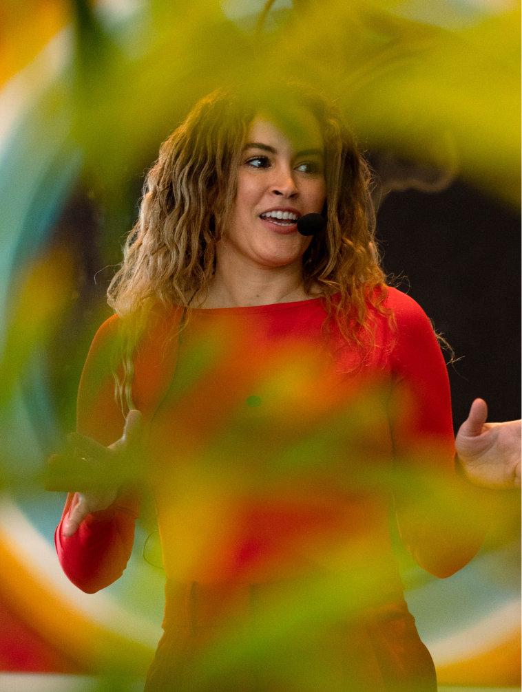Susana speaking on stage during a wellness event