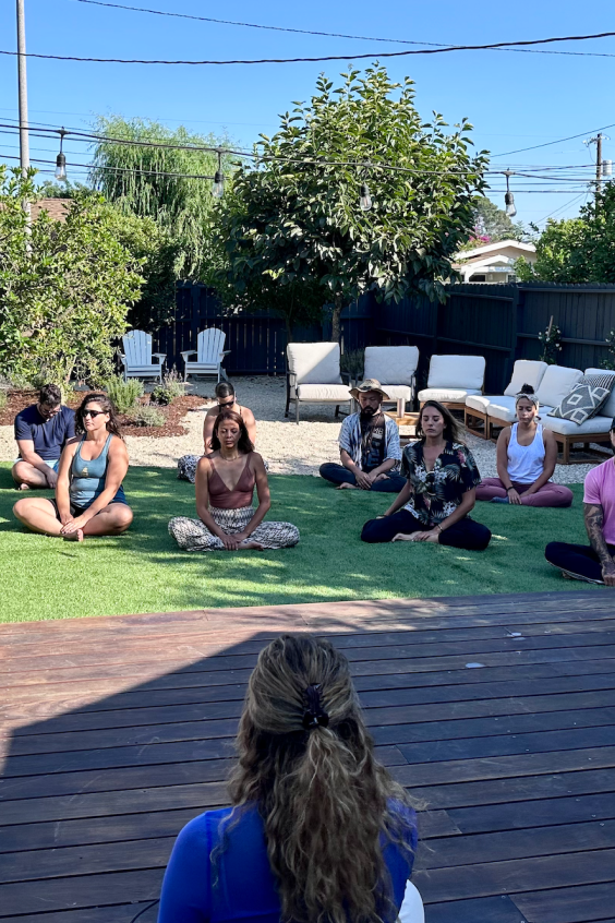 Group meditating outdoors during a wellness event