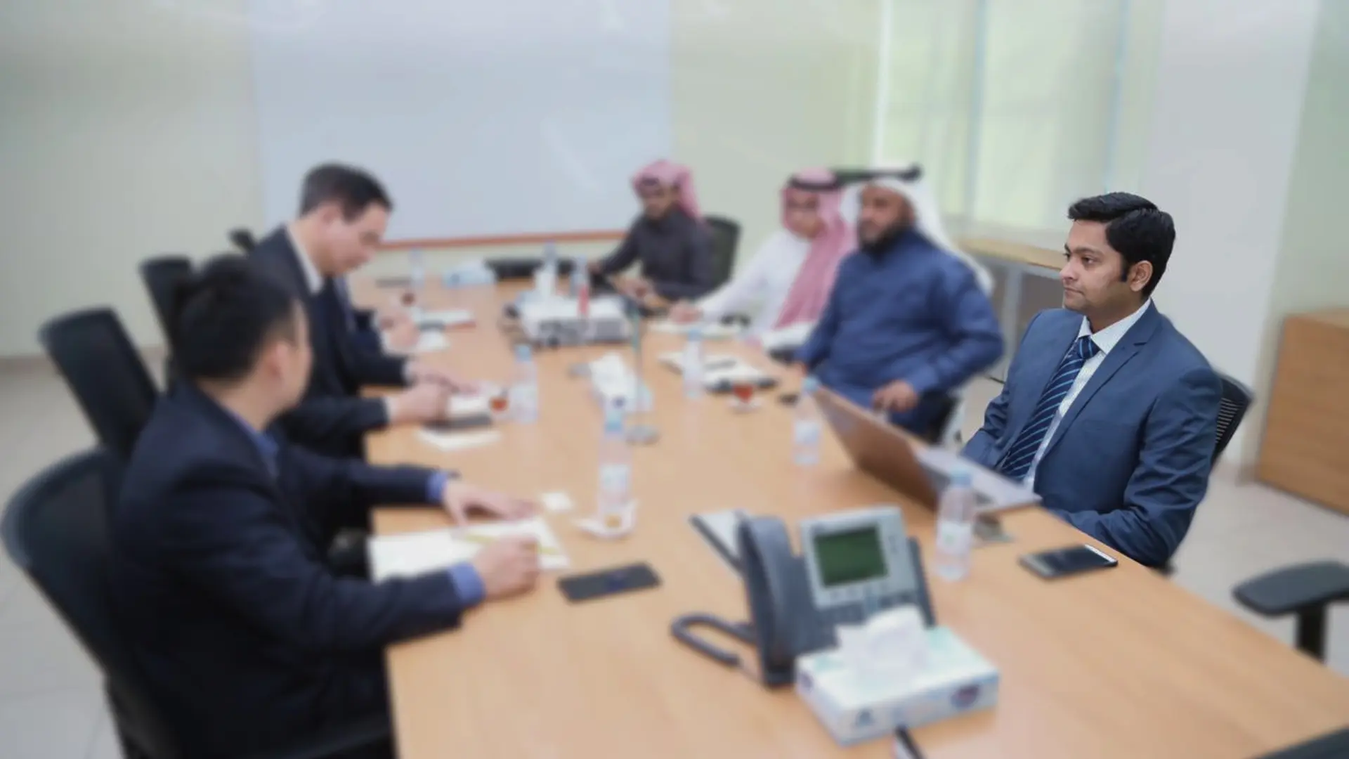 Basil Mughal in discussion with colleagues around a boardroom table