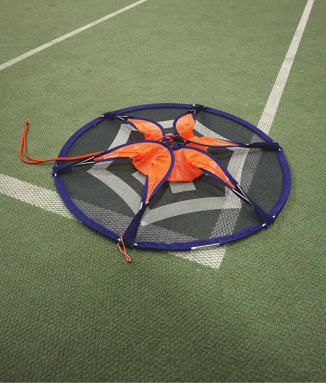 The Pannaball goal folded flat on a green indoor sports floor, ready to slide into the carry bag