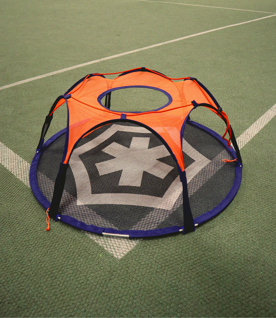 Close-up of the assembled Pannaball goal with orange net and blue frame on a green indoor sports floor