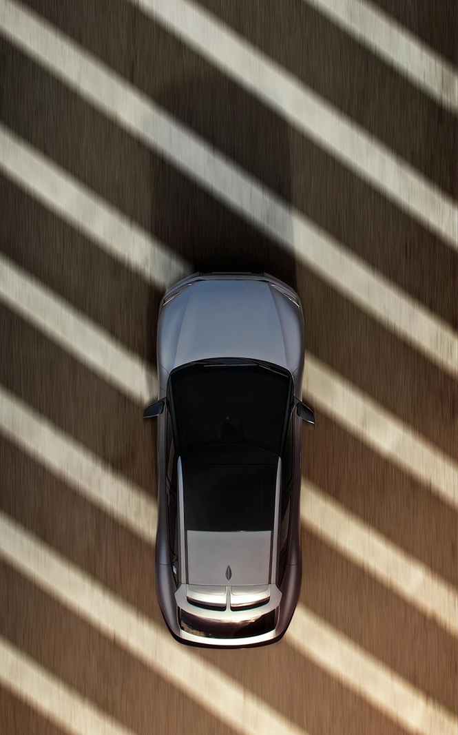 Vue aérienne d'une voiture grise sur une route avec des rayures d'ombre diagonales.