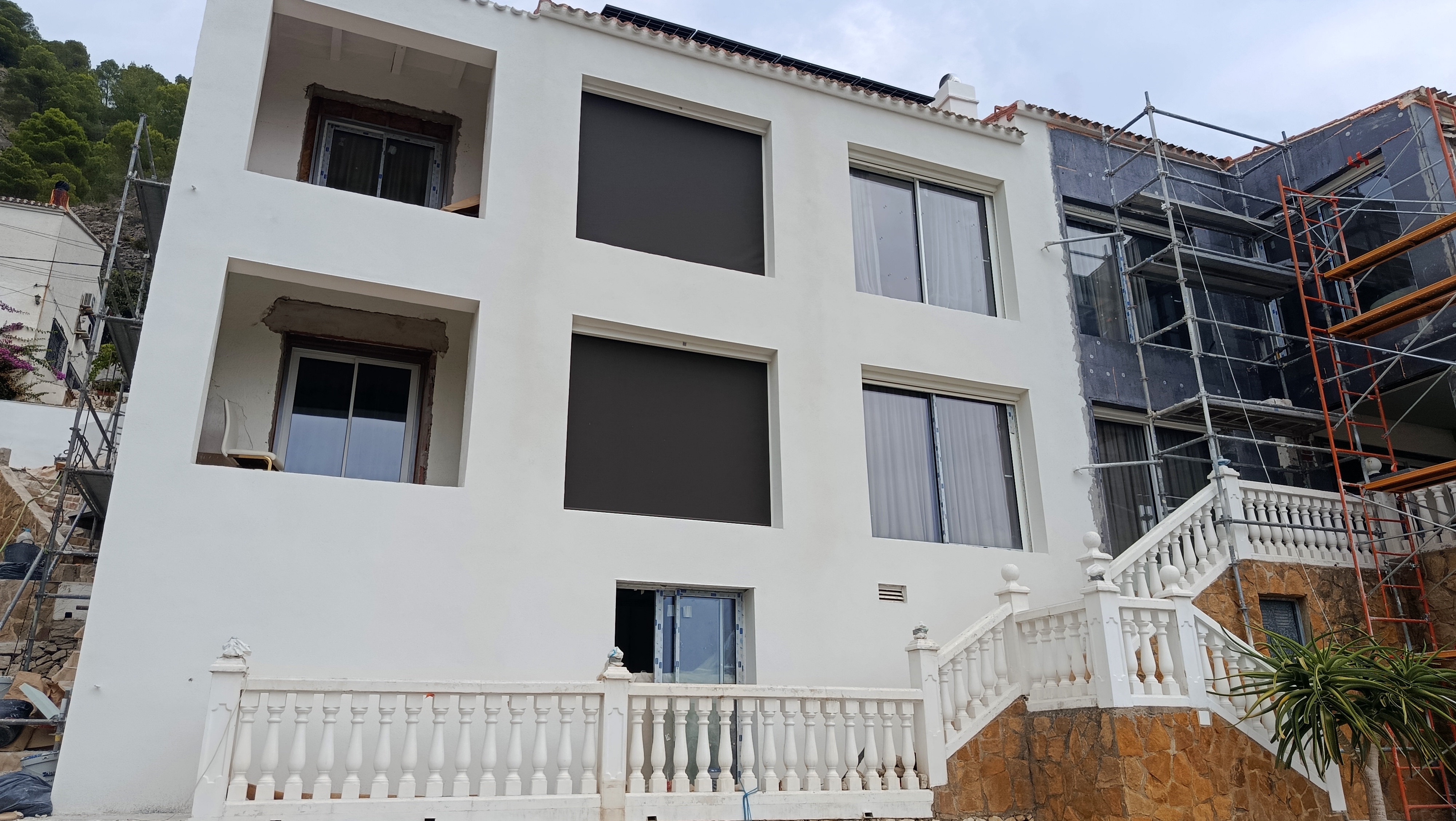 Rehabilitación de fachada con andamios y zonas ya revestidas