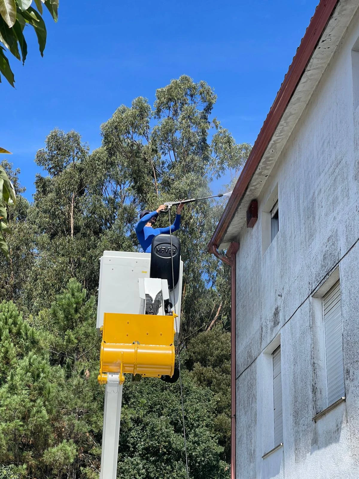 Operario limpiando la fachada desde una plataforma elevadora en Alicante