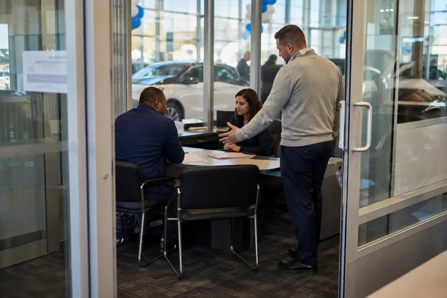 A dealership customer handoff taking place at the entrance to an F&I office.
