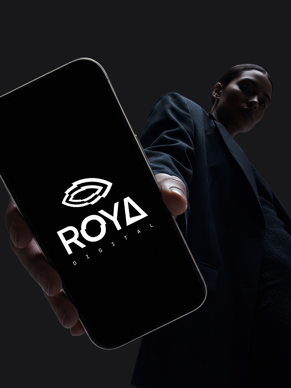 A woman holding a phone with the Roya Digitals logo presented on the screen