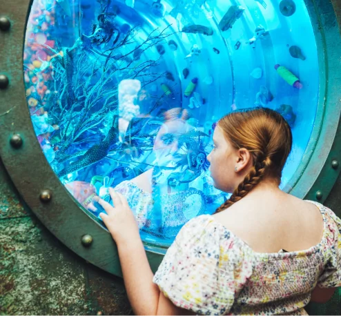 Young girl gazing at an underwater-themed art installation during a Wake The Tiger Calm Session
