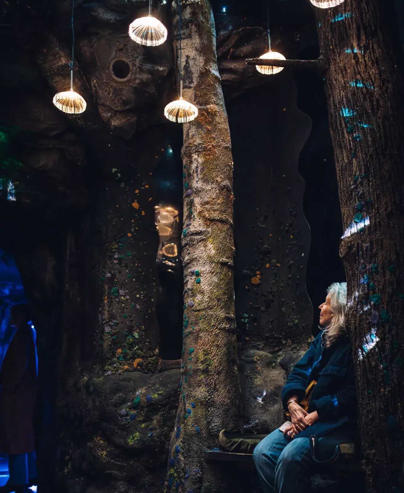 Woman sitting inside the immersive forest exhibit at Wake The Tiger