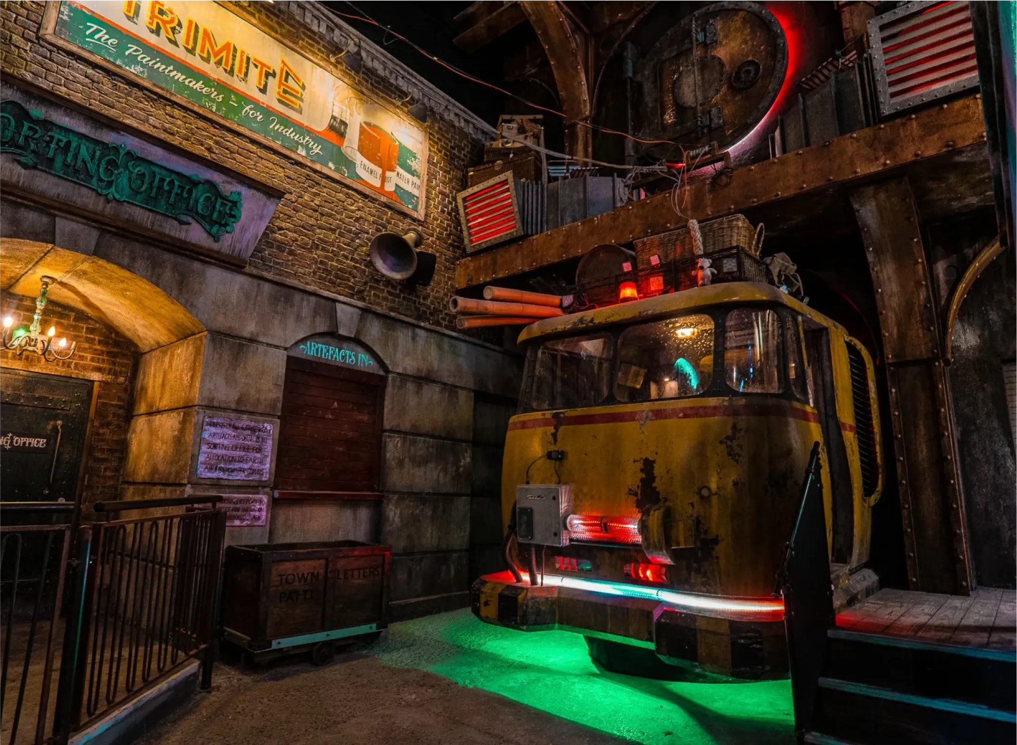 Industrial-themed indoor set with a weathered yellow vehicle, brick walls, vintage signage, and colorful lighting effects.