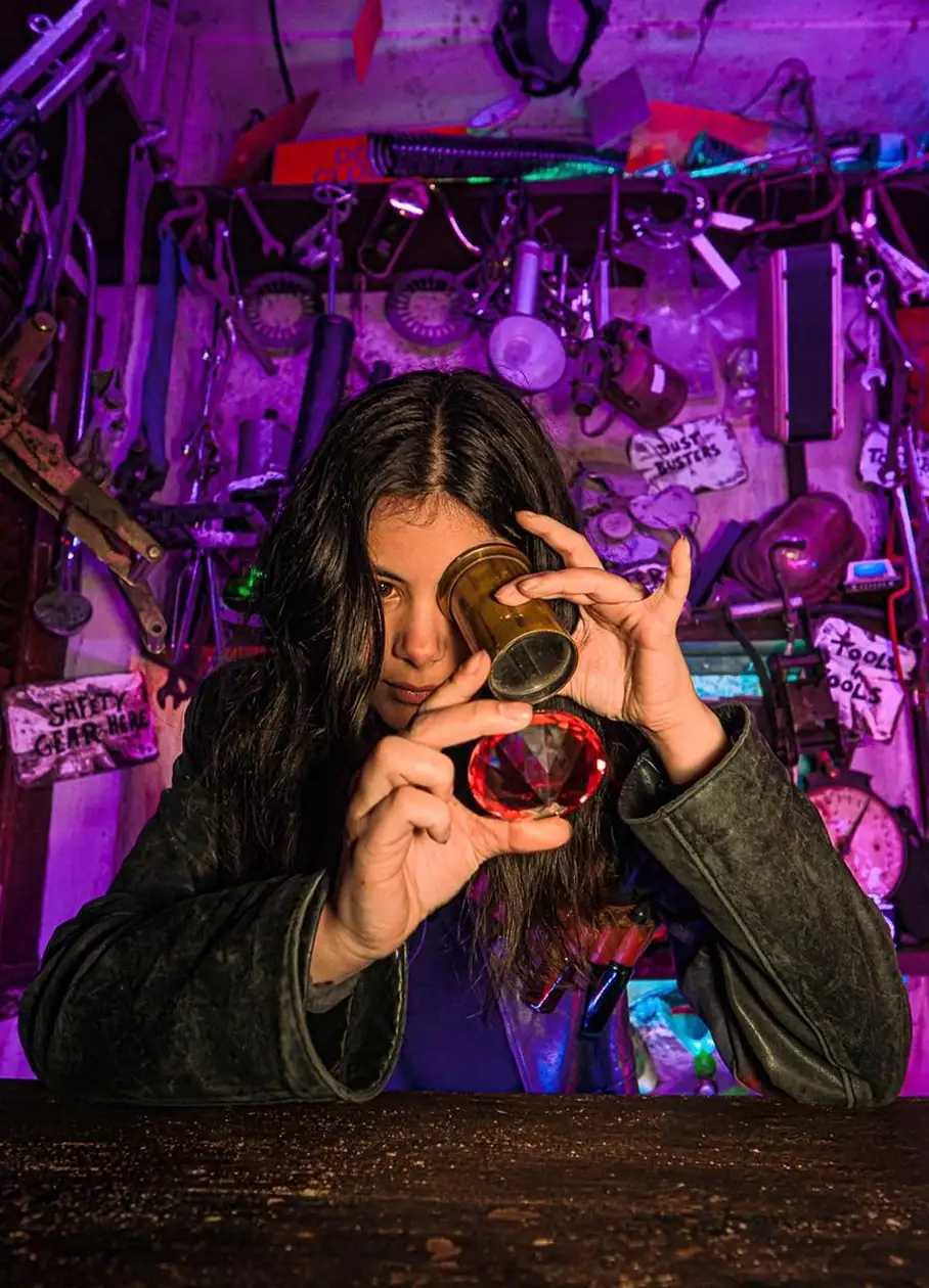 Woman holding a magnifier and red crystal inside an immersive room at Wake The Tiger.