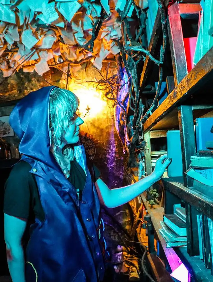 Woman in a hooded vest exploring the glowing Secret Library room at Wake The Tiger.