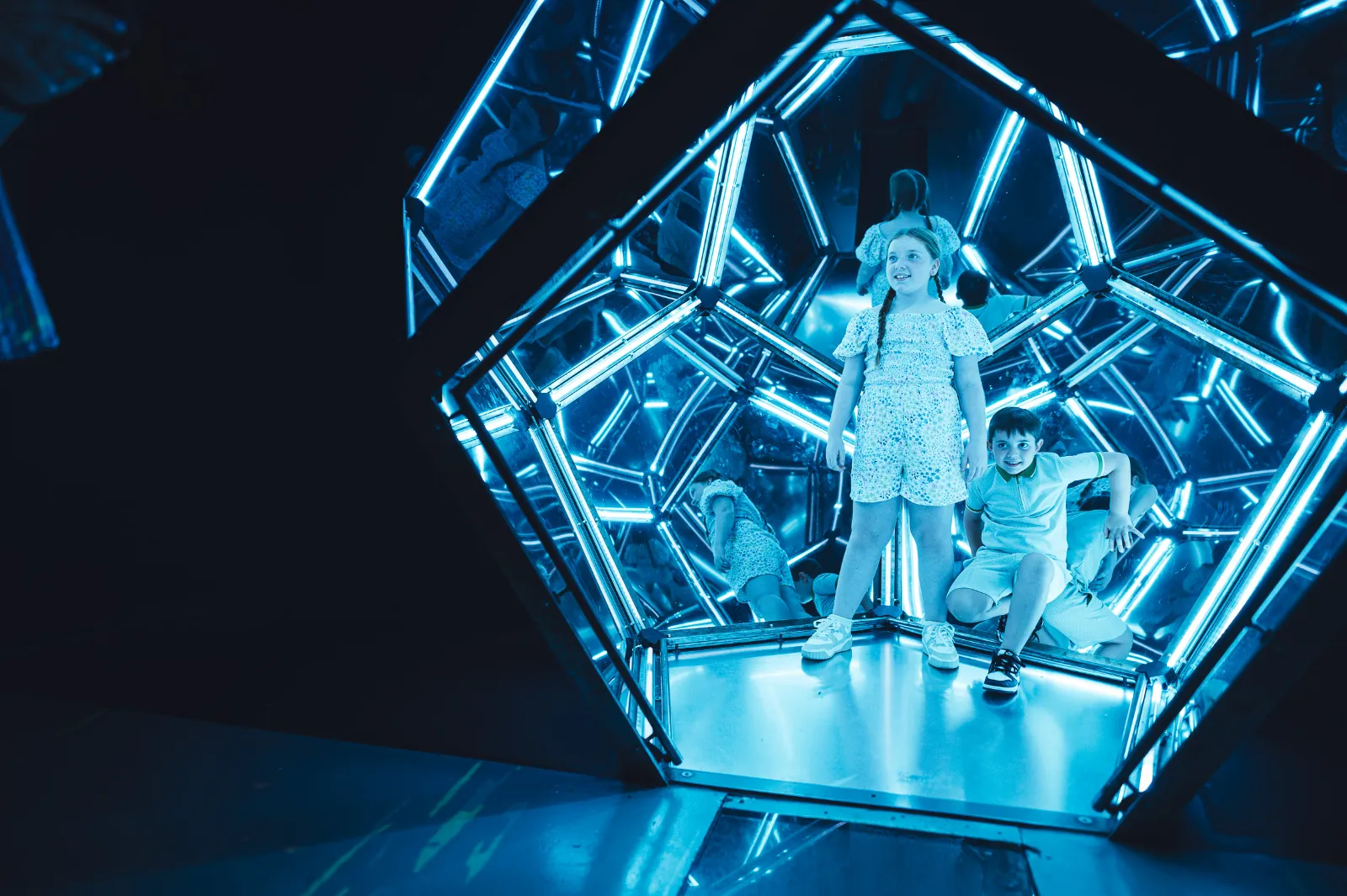Kids enjoying a mirrored room lit in blue at Wake The Tiger