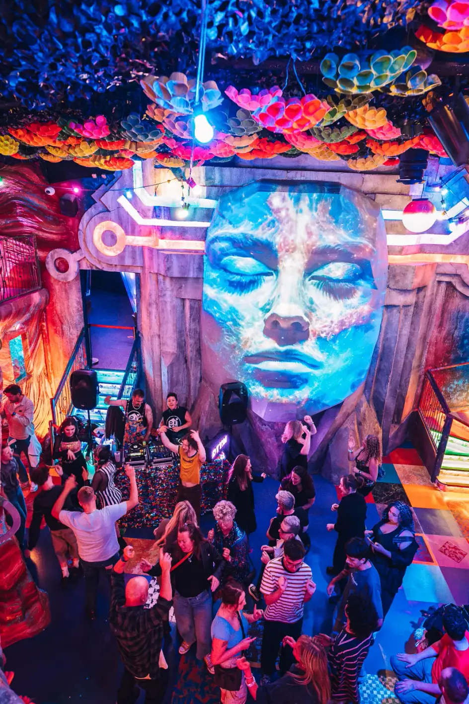 Neon-lit dance floor with a projected face at a Wake The Tiger After Hours event