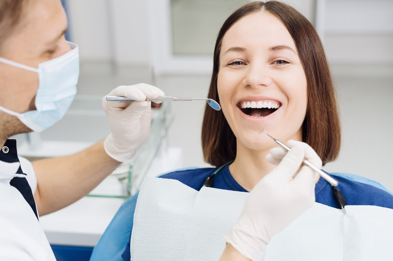 Dentist checking a smiling patient's teeth with a mirror and probe