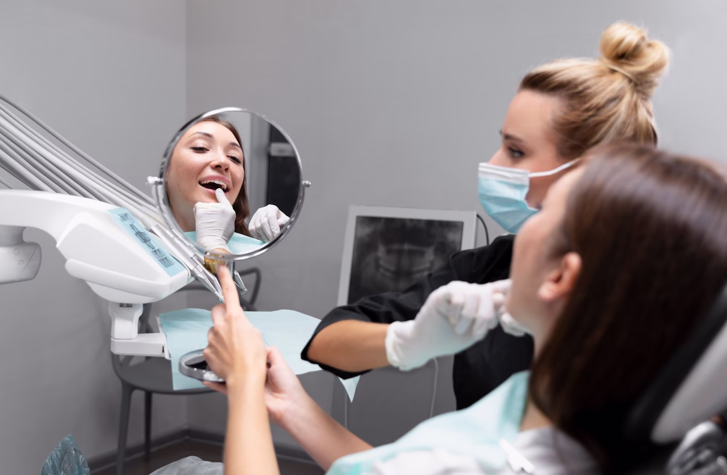 Patient in the dental chair during treatment, with x-rays on the screen behind