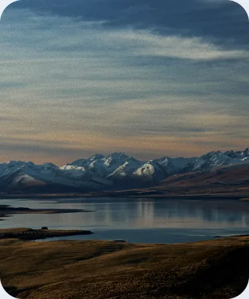 Snow-capped mountain range reflected in a calm lake at sunset